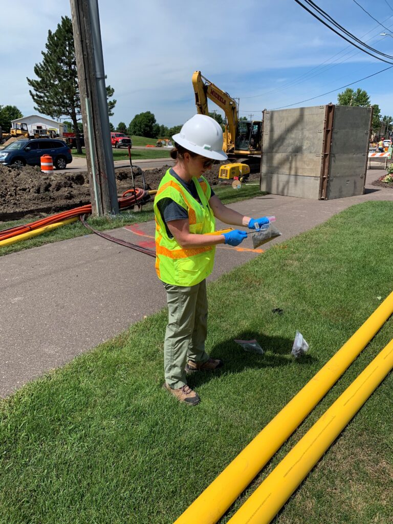 Due diligence contamination assessment Phase One Environmental Site Assessment in Minnesota. Mandy Bohnenblust environmental scientist performing field screening during construction monitoring.